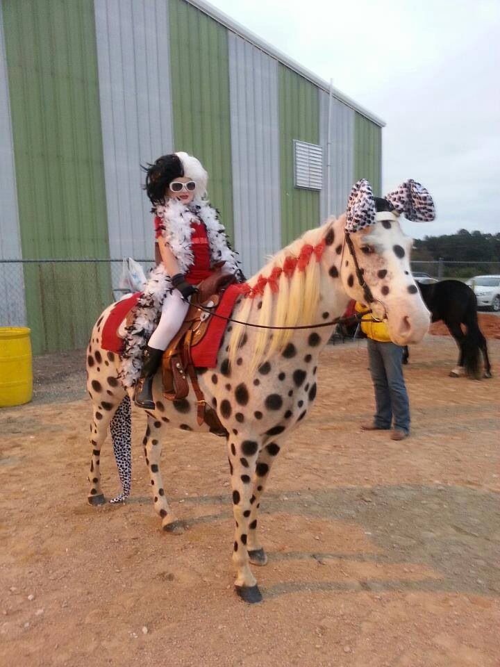 a woman in costume riding on the back of a dalmatian horse