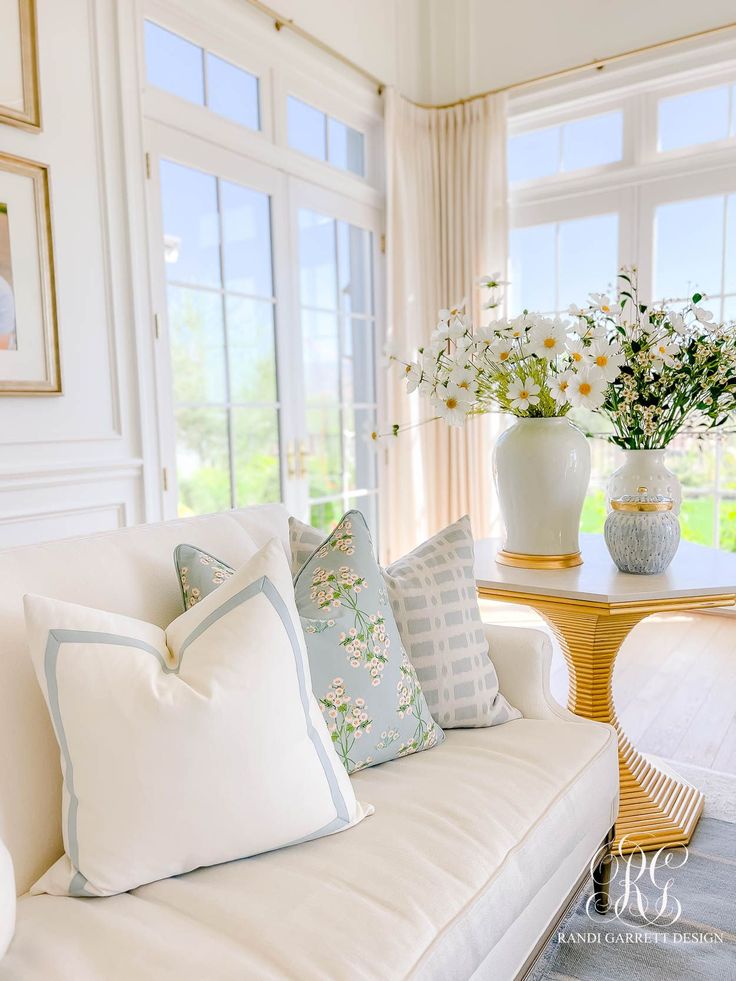 a living room filled with lots of furniture and flowers in vases on the table