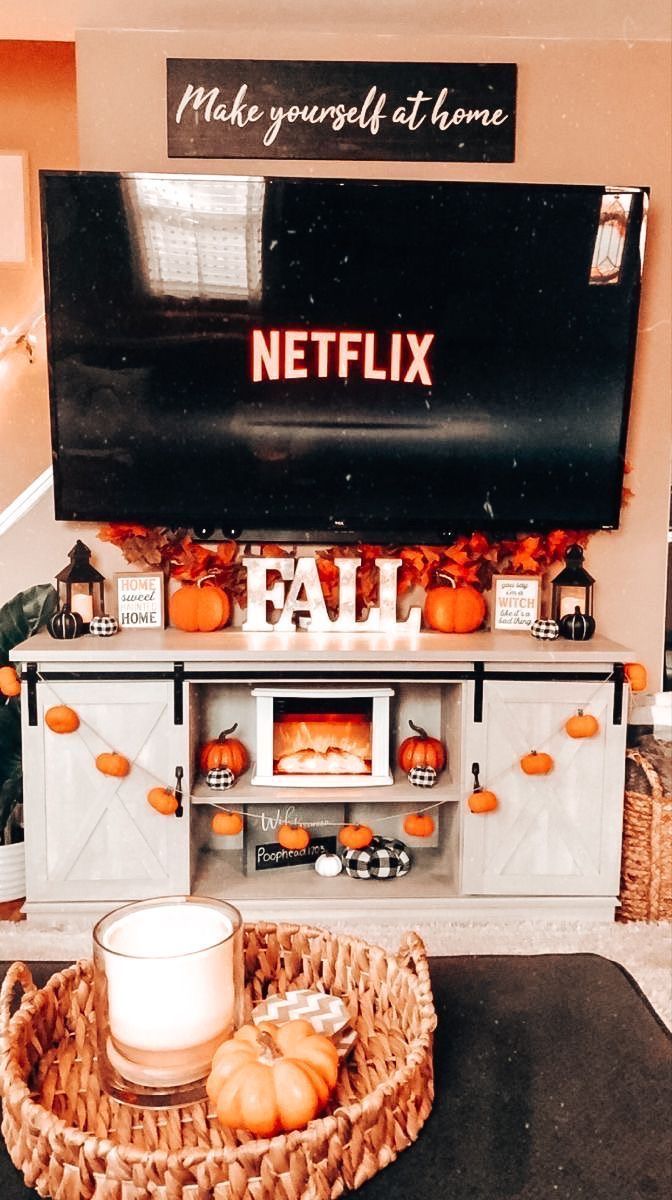 a television sitting on top of a tv stand next to a basket filled with pumpkins