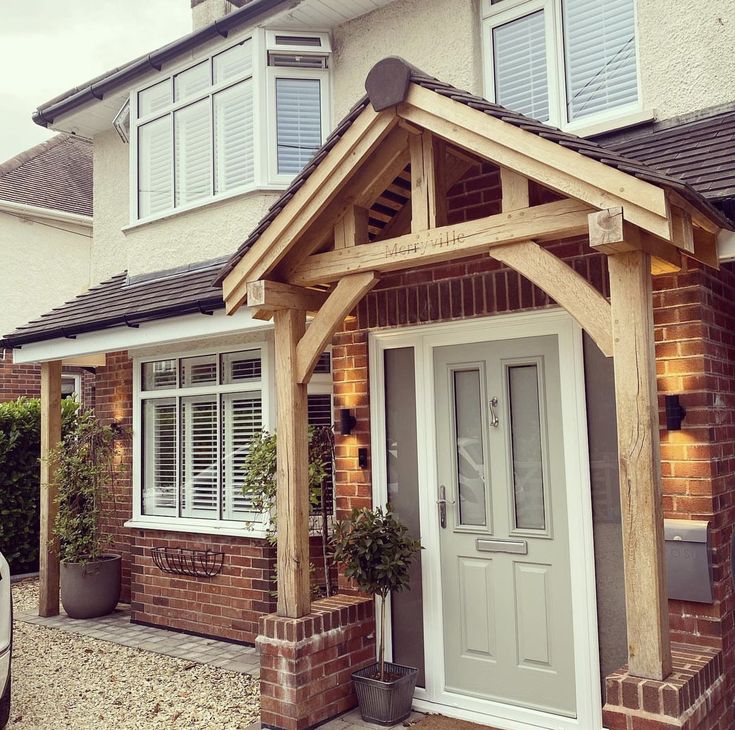 a house with a white front door and wooden frame on the outside, next to a car parked in front of it