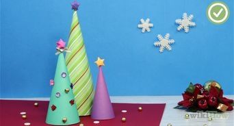 two paper christmas trees on a table with confetti and candy in the background