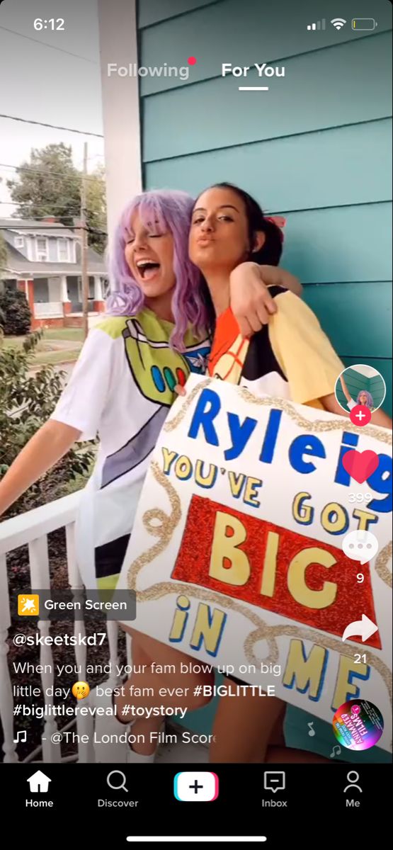 two women standing next to each other in front of a house with an advertisement on it