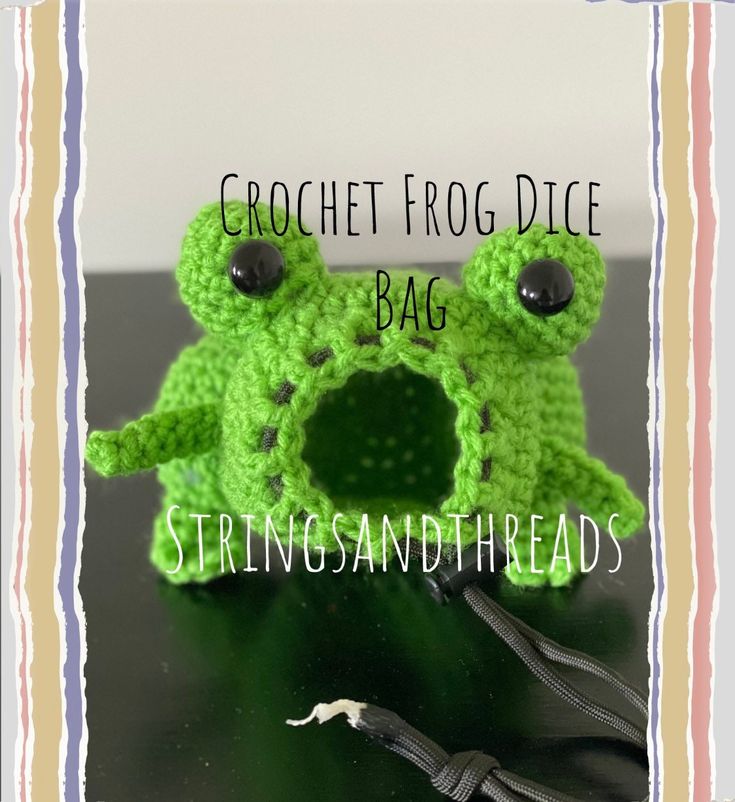 the crochet frog dice bag is sitting on top of a table with scissors