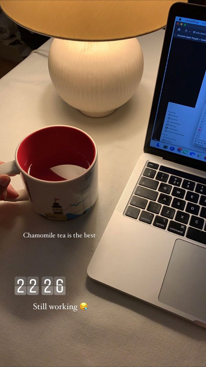 a laptop computer sitting on top of a table next to a cup