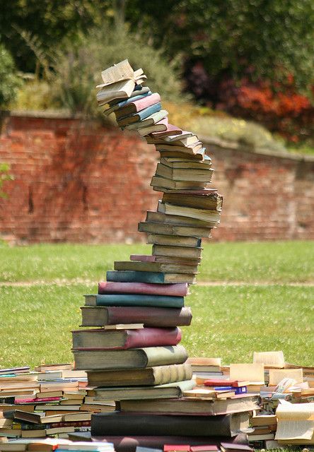 a stack of books sitting on top of a lush green field