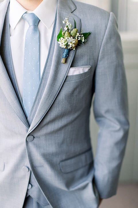 a man in a gray suit and blue tie is wearing a flower boutonniere