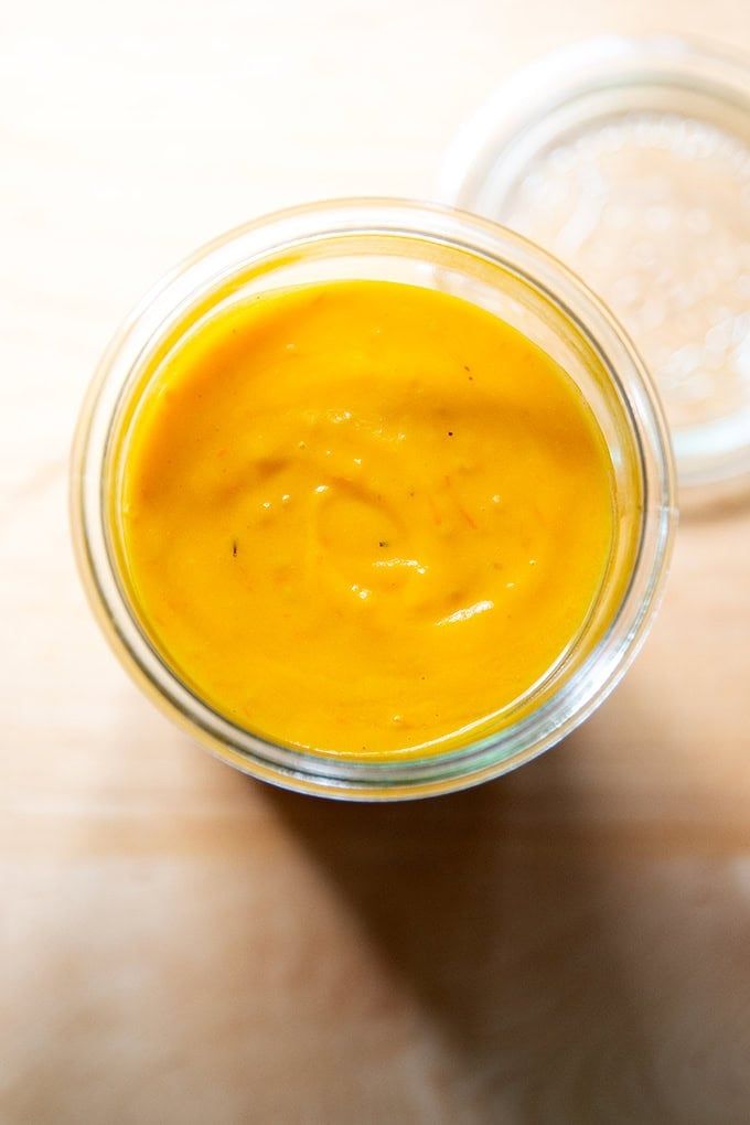 a glass jar filled with yellow liquid sitting on top of a wooden table next to another container