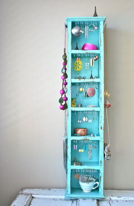 a blue cabinet with jewelry hanging from it's sides