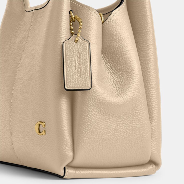 Find COACH Lana Shoulder Bag 23 on Editorialist. The Coach Lana Shoulder Bag is crafted from polished pebble leather and features a center slip compartment, two open compartments, and a detachable crossbody strap for versatile wear. This bag is also detailed with the brand's signature hardware. Elegant Beige Pebbled Leather Shoulder Bag, Modern Pebbled Leather Bag For Everyday Luxury, Modern Pebbled Leather Bag, Formal Beige Pebbled Leather Shoulder Bag, Luxury Cream Smooth Grain Bag, Classic Cream Textured Leather Bag, Formal Cream Bag With Smooth Grain, Everyday Luxury Beige Shoulder Bag With Smooth Grain, Luxury Cream Textured Leather Satchel