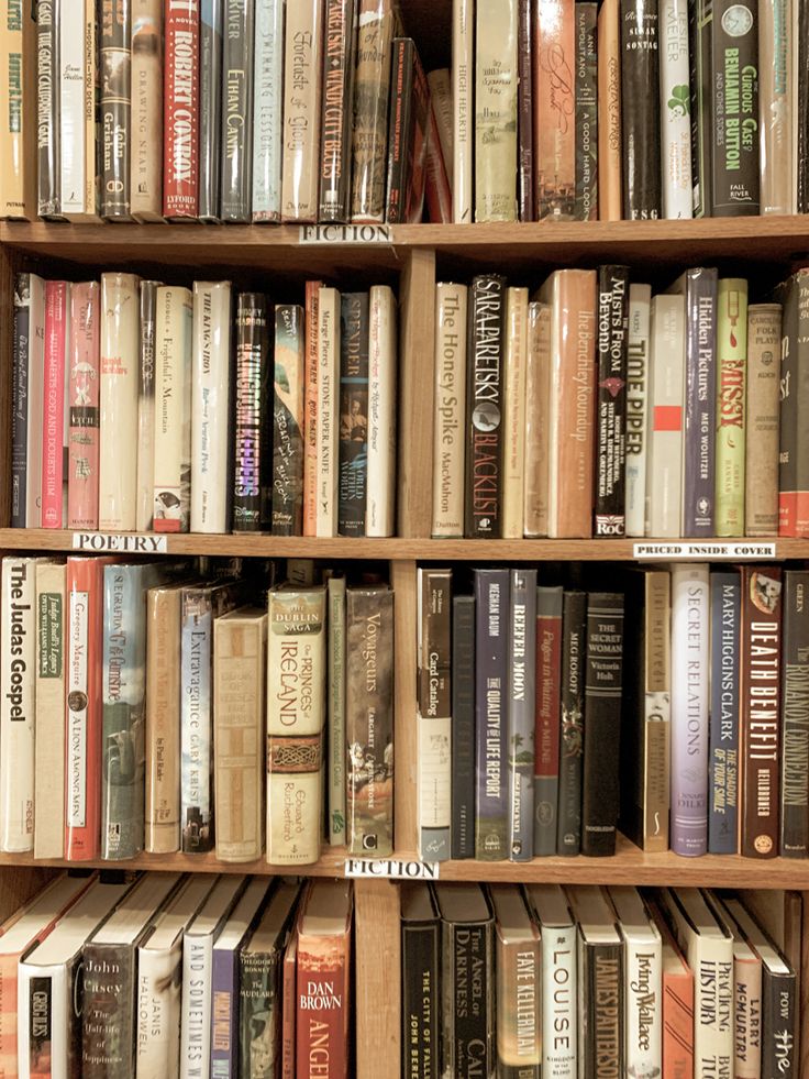 a bookshelf filled with lots of different types of books on top of wooden shelves