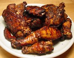 a white plate topped with chicken wings on top of a wooden table