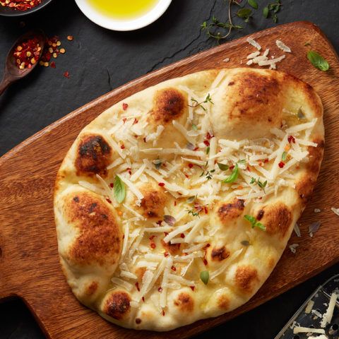 a pizza sitting on top of a wooden cutting board next to other food and utensils