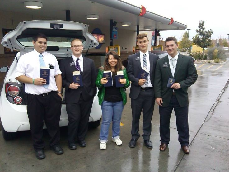 four men and two women standing in front of a car with their awards on it