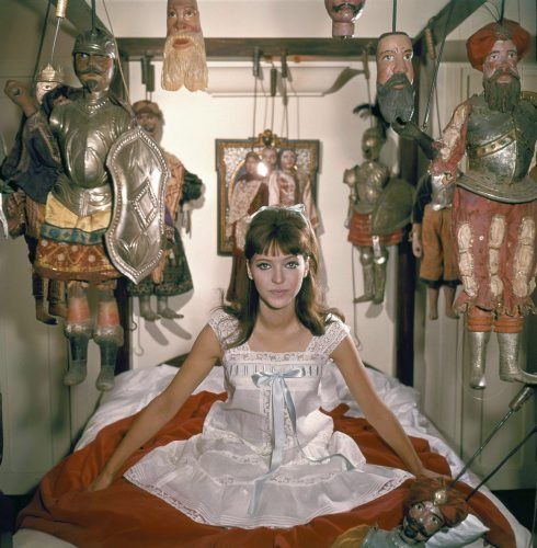 a woman sitting on a bed in front of many mannequins