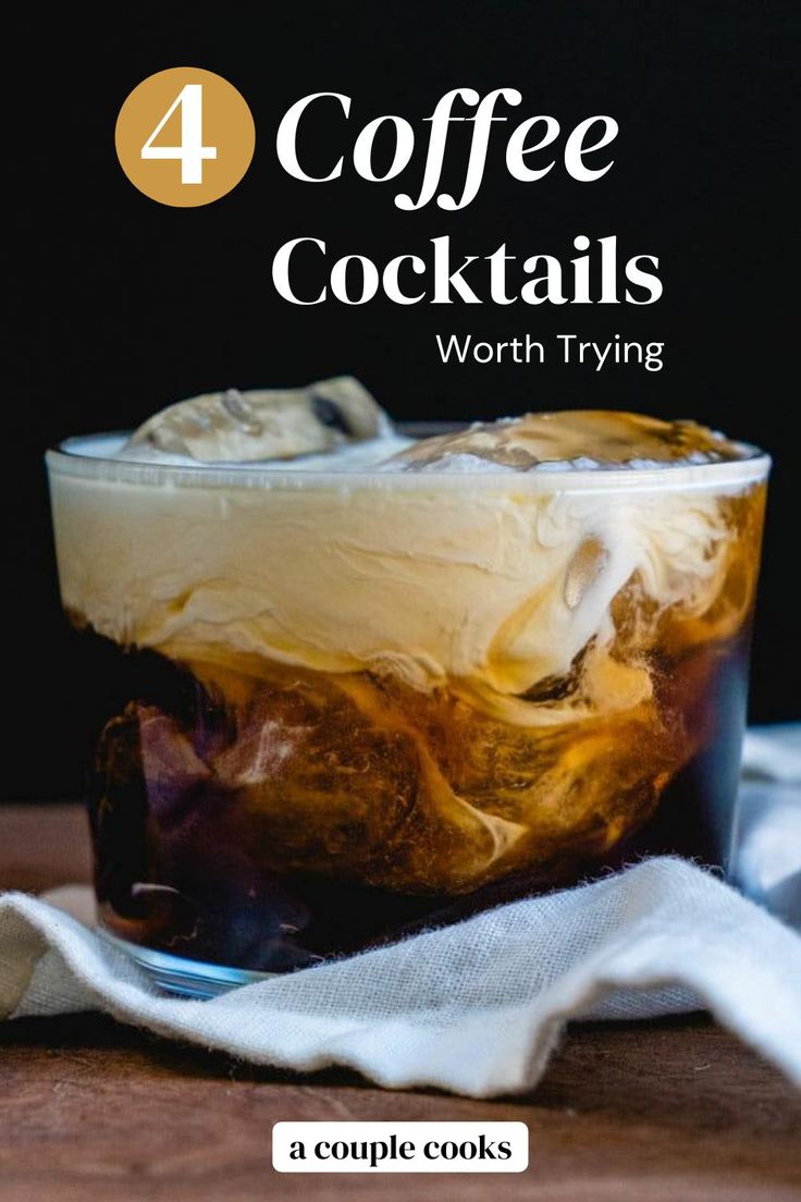 a glass filled with liquid and ice sitting on top of a wooden table next to a napkin