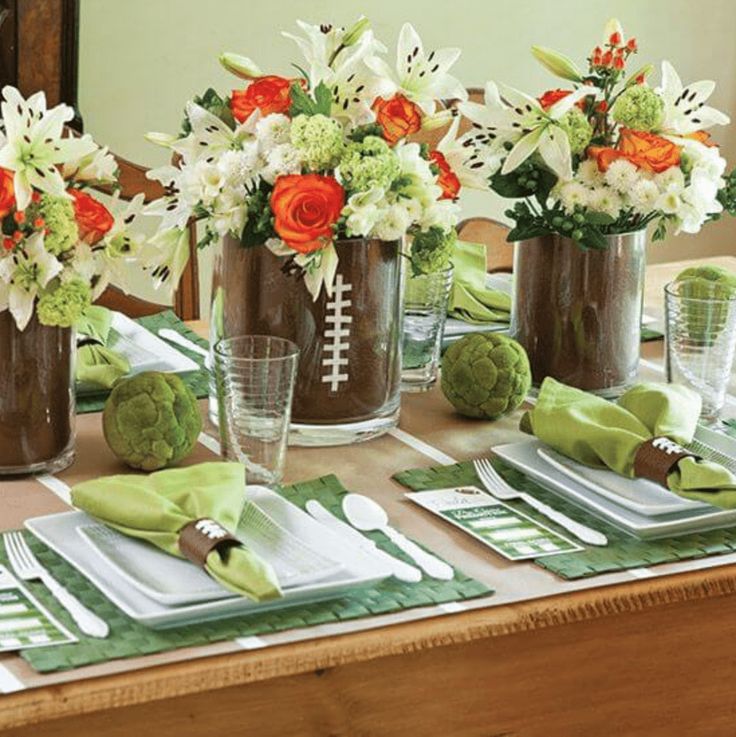 the table is set with green napkins and vases filled with flowers, plates and utensils