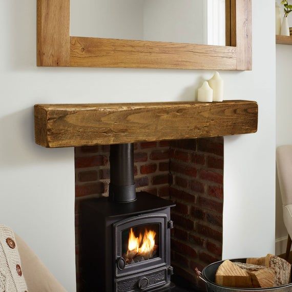 a wood burning stove sitting inside of a living room next to a wall mounted mirror