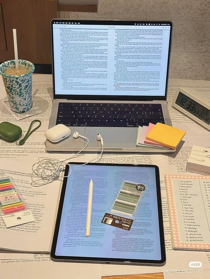 an open laptop computer sitting on top of a table next to a tabletop with papers and pens