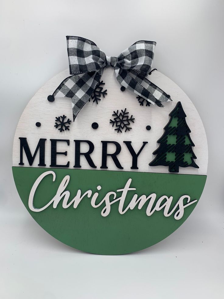 a merry christmas sign hanging from the side of a white and green circle with snowflakes on it