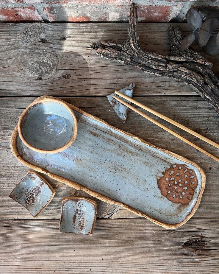 a bowl and chopsticks are sitting on a wooden table next to some rocks