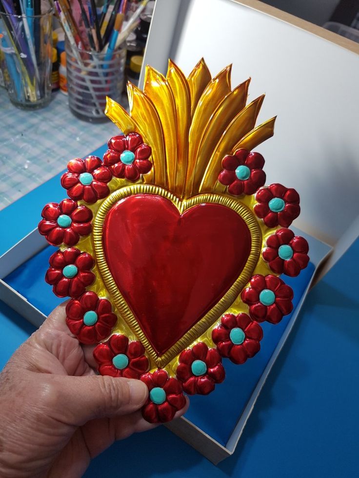 a hand holding up a heart shaped decoration