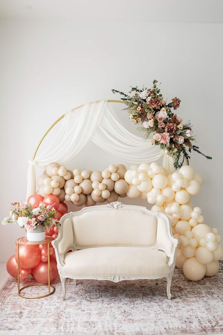 a white couch sitting next to a table with balloons and flowers on top of it