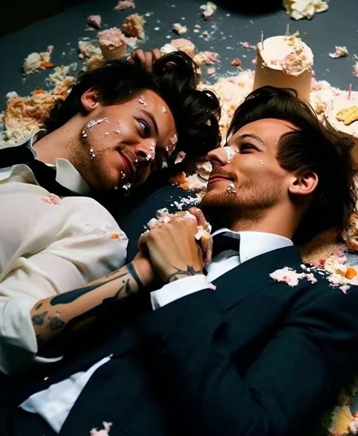 two men laying on the ground with confetti all over their face and hands