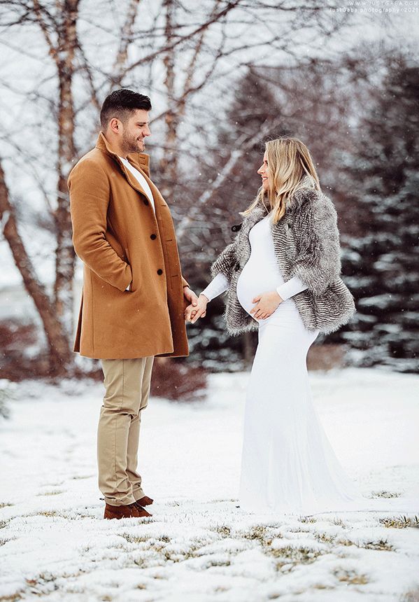 a man and woman standing in the snow holding hands