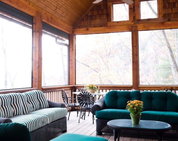 a living room filled with furniture and windows covered in wood paneling on top of a wooden floor