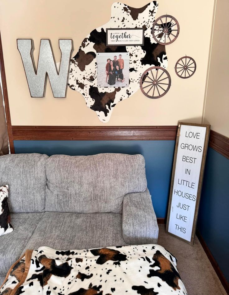 a living room with a gray couch and cow print blanket