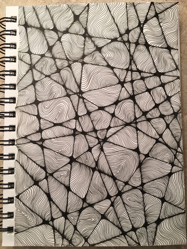 a spiral notebook with black and white patterns on it, sitting on a table top