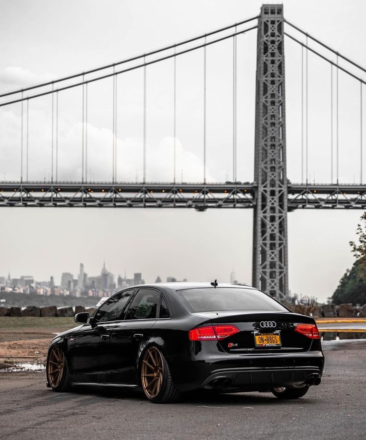 a black car parked in front of a bridge