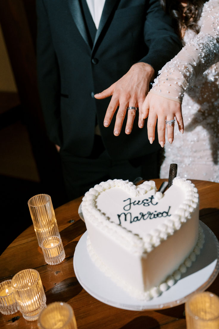 a newly married couple cutting into their heart shaped cake with the bride and groom behind them