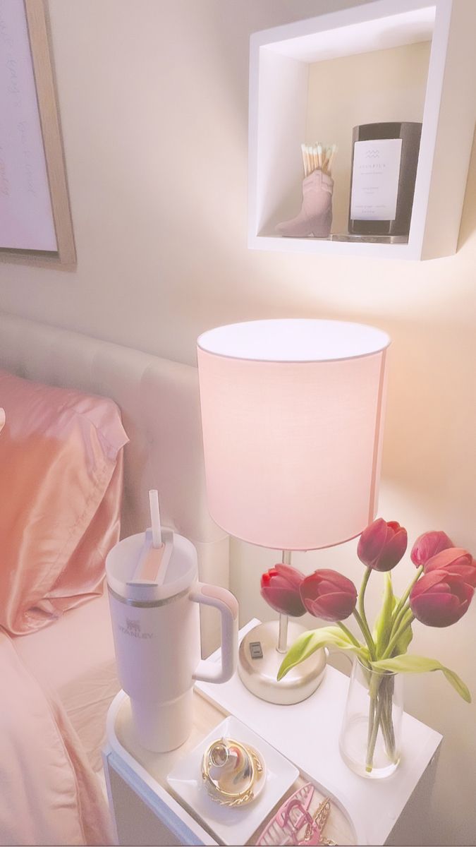 a pink lamp sitting on top of a table next to a bed