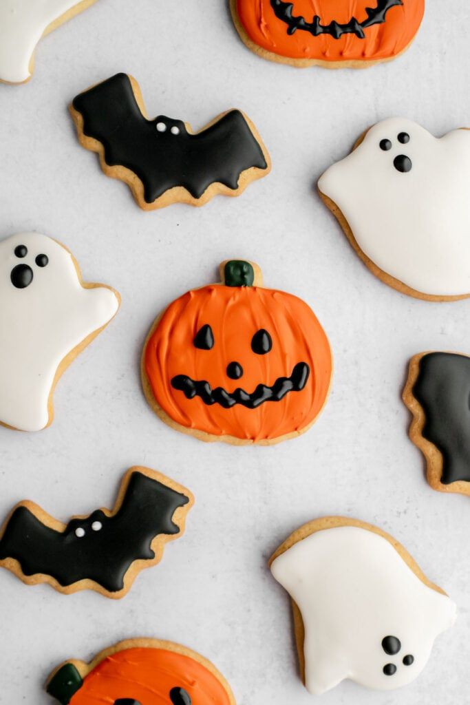 halloween cookies decorated with icing and sprinkles on a white tablecloth