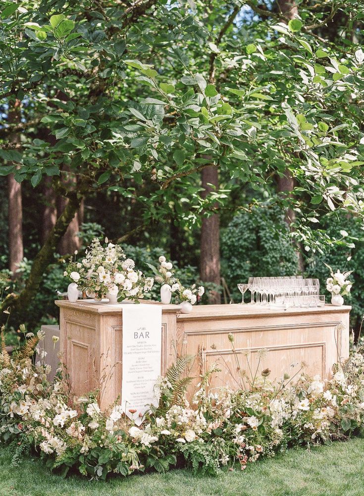 an outdoor bar surrounded by flowers and greenery in the middle of a park area