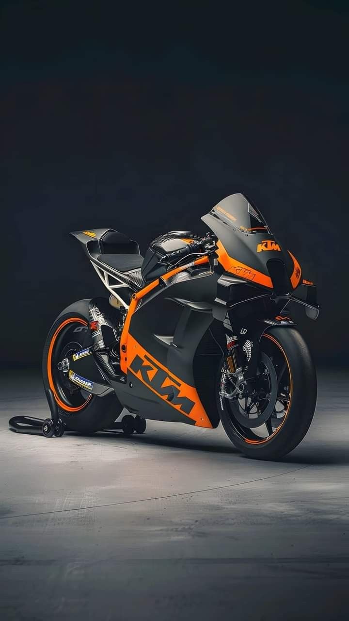 an orange and black motorcycle parked in a dark room