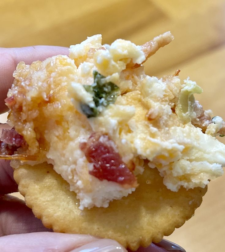 a person holding up a pastry with toppings on it