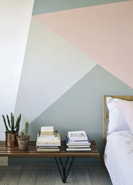 a bed room with a neatly made bed and a wall painted in pastel colors