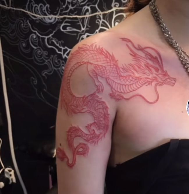 a woman with a dragon tattoo on her arm and chest, wearing a black top