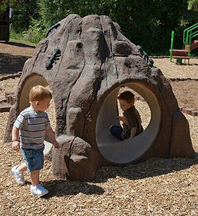 two young boys playing in a play area at a park with rocks and climbing equipment