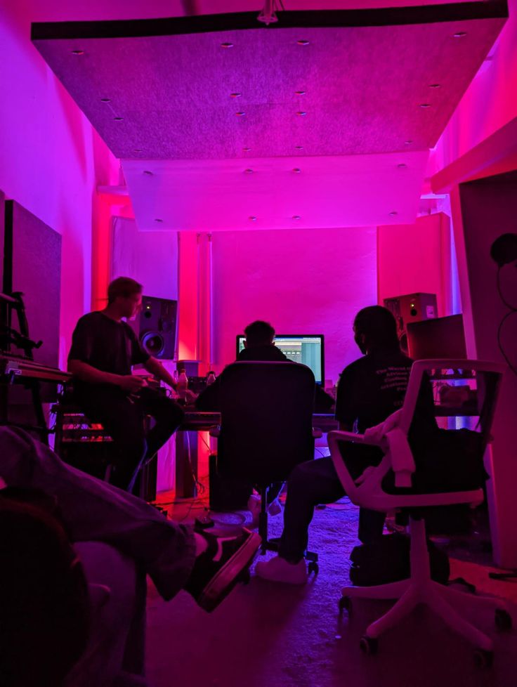 three people sitting in an office with purple lighting