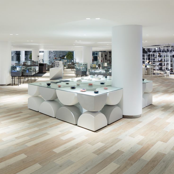 a large room filled with lots of white furniture and glass tables on top of hard wood flooring