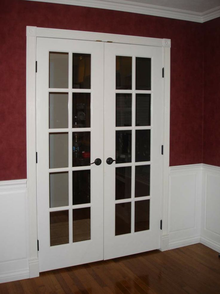 two white french doors in a room with red walls