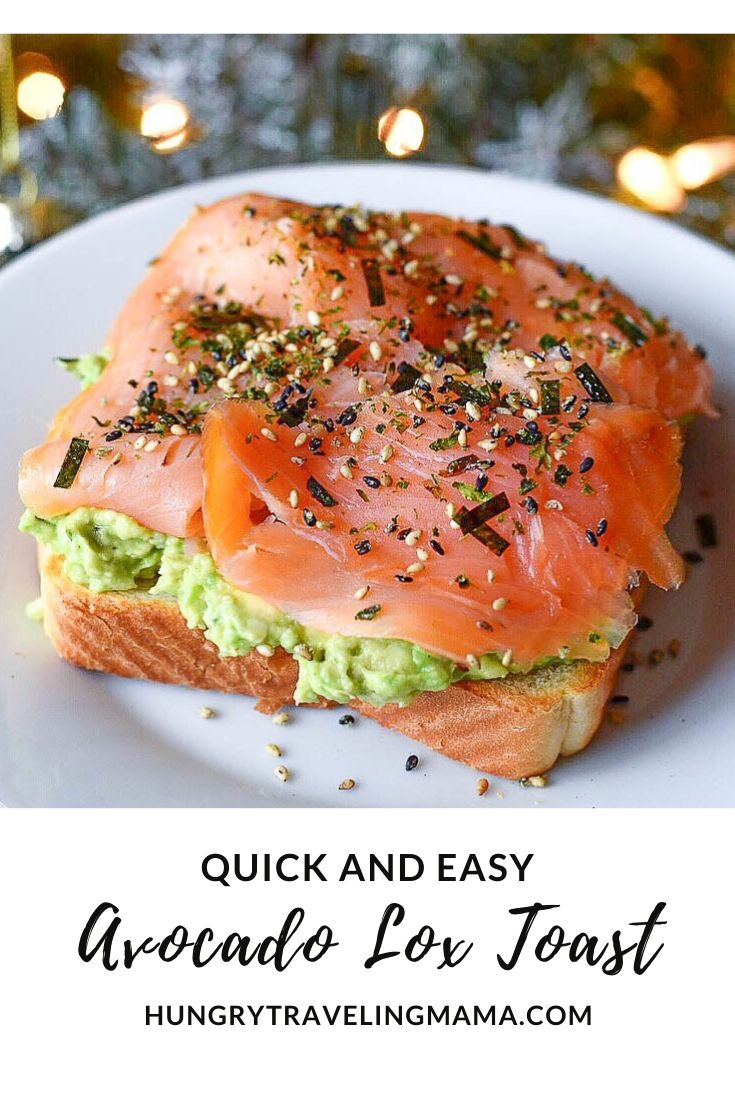 a sandwich with salmon and avocado on it in front of a christmas tree