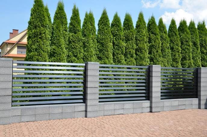 a modern fence is shown in front of a brick walkway and trees on the other side