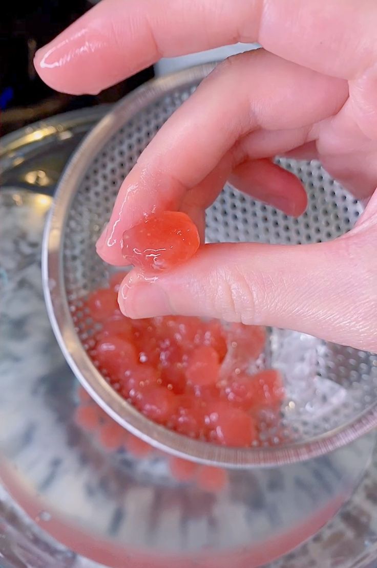 a person is squeezing jelly into a bowl with their fingers on the glass and holding it in one hand