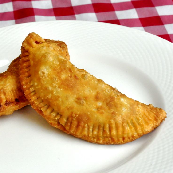 two pastries on a white plate with a red and white checkered tablecloth