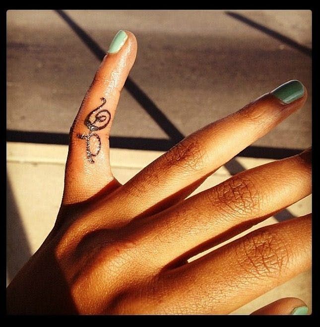 a person's hand with a small tattoo on the middle finger and an ombrephant in the middle