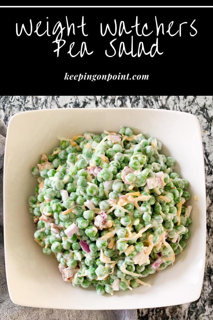 a white bowl filled with peas and pasta on top of a table next to a fork